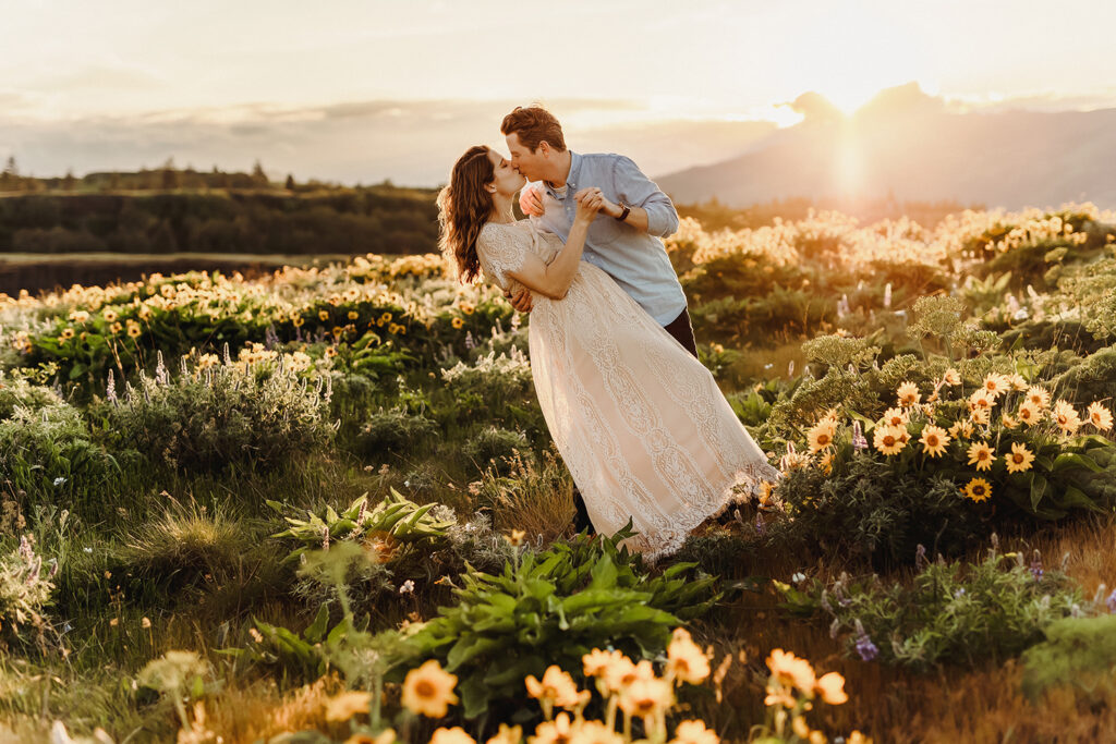 Husband dips wife and kisses her in a sea of yellow wildflowers at Rowena Crest.