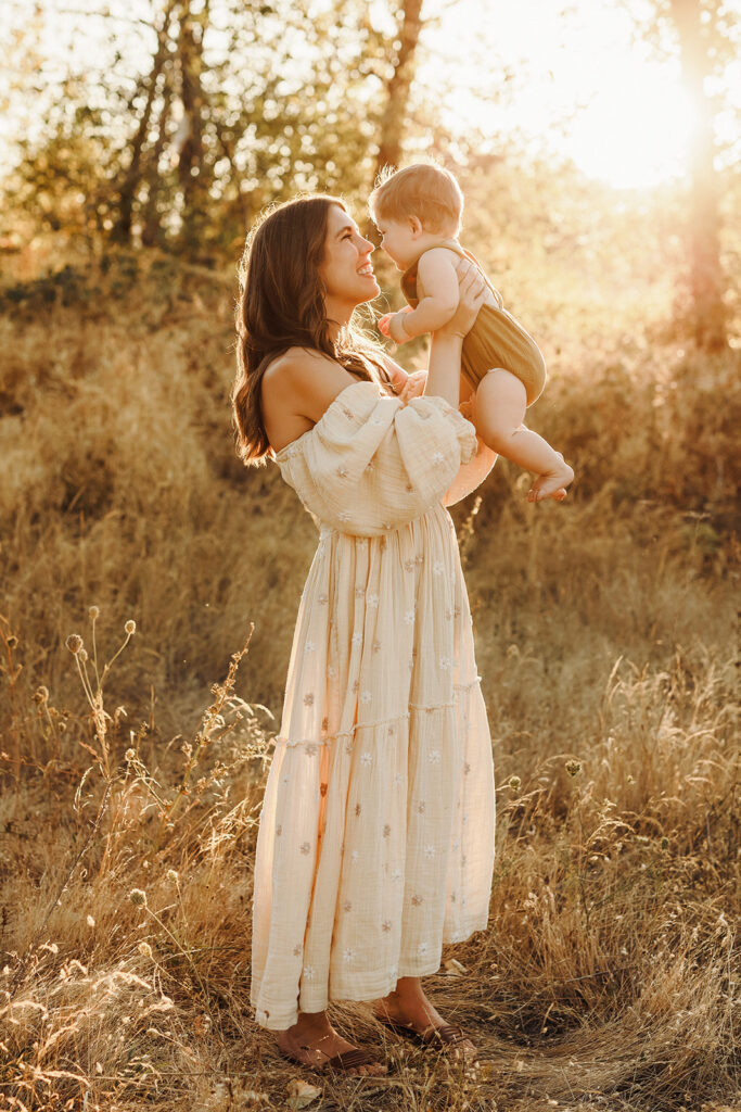 A mom holds her baby boy up in the air and brings them nose to nose, as captured by a Vancouver Washington Photographer who focuses on capturing authentic moments.
