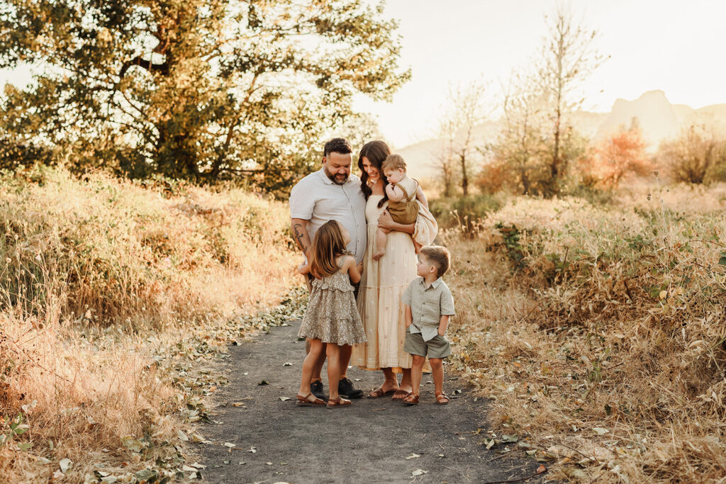 A family stands together in beautiful light, smiling at each other and having fun - as captured by a Vancouver Washington Photographer who focuses on capturing authentic moments.