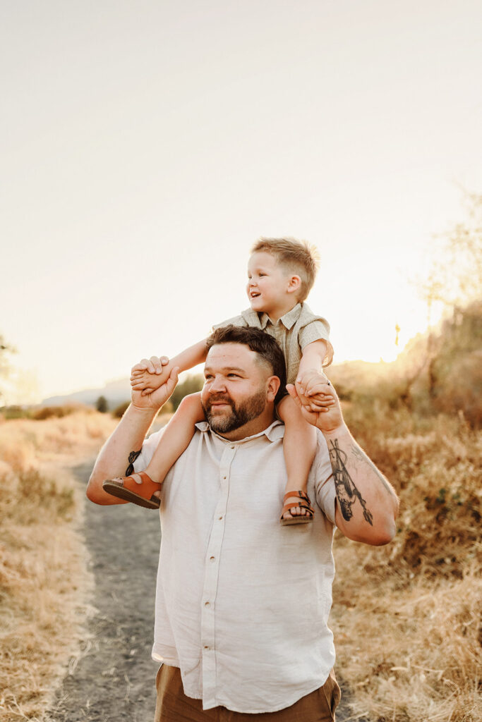 A dad holds his little boy up on his shoulders as they take in the view of the columbia river gorge together, as captured by a Vancouver Washington Photographer who focuses on capturing authentic moments.