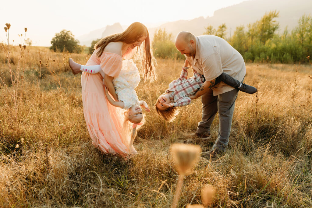 A family plays together in a field near Vancouver Washington while a photographer captures their joy and connection.