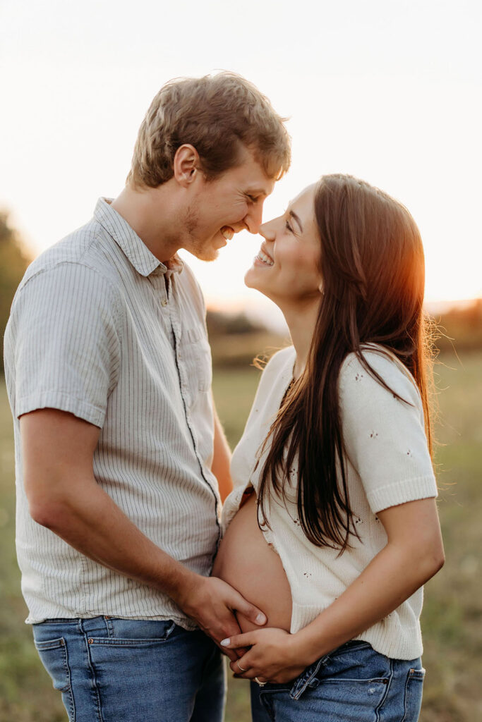 Maternity couple holding bare belly and smiling lovingly at each other in a candid moment Vancouver Washington
