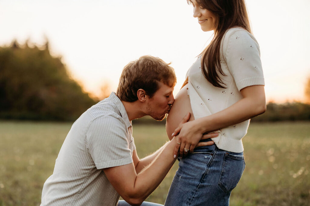 couple embracing and dad kissing bare belly during maternity session in Vancouver Washington