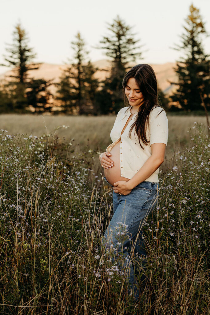 mom in jeans and cardigan maternity session outdoors Vancouver Washington